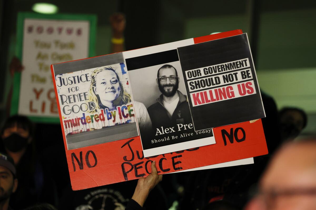 A sign is raised in support of Renee Good and Alex Pretti at a candlelight vigil in Los Angeles.