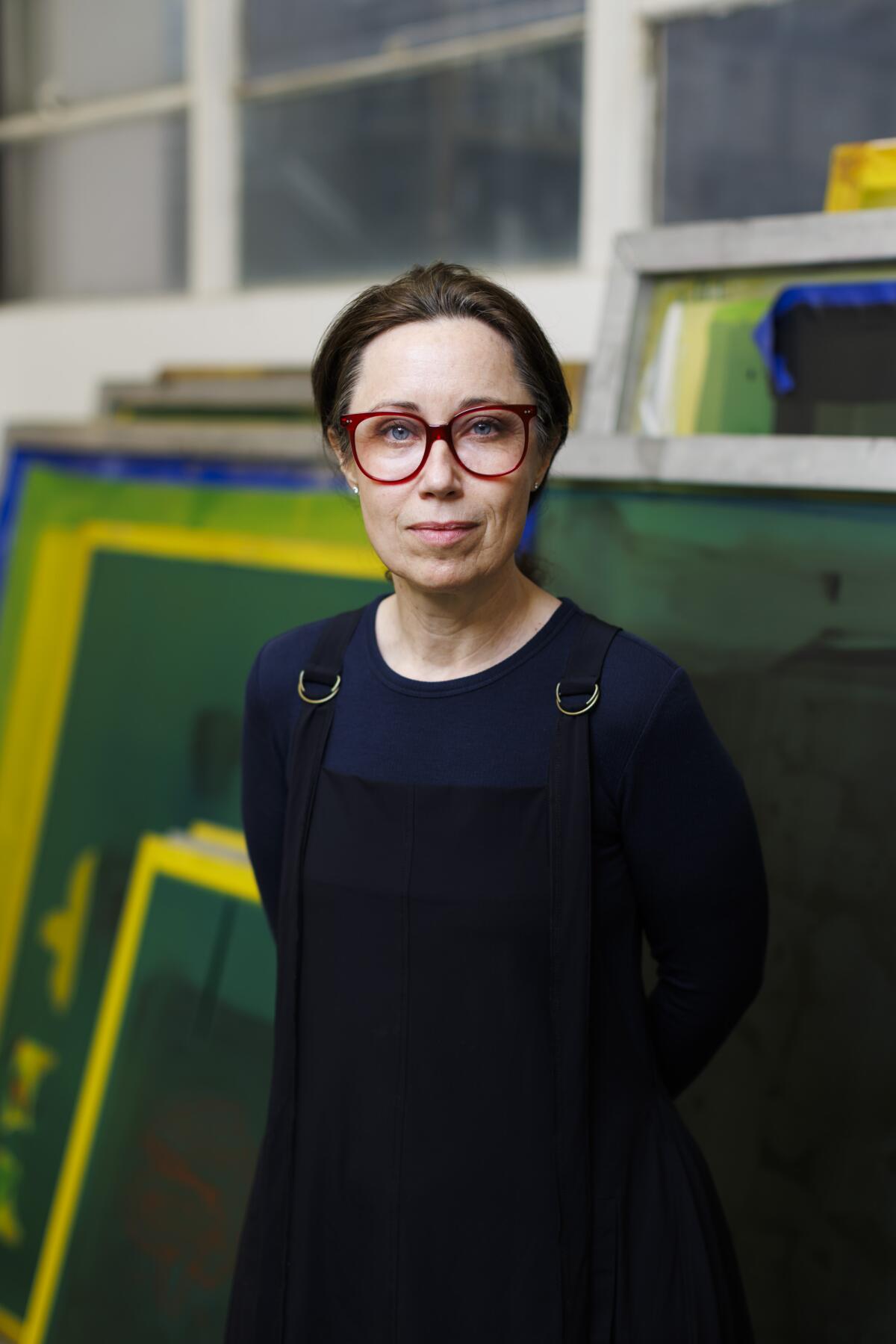 A woman standing in front of green canvases