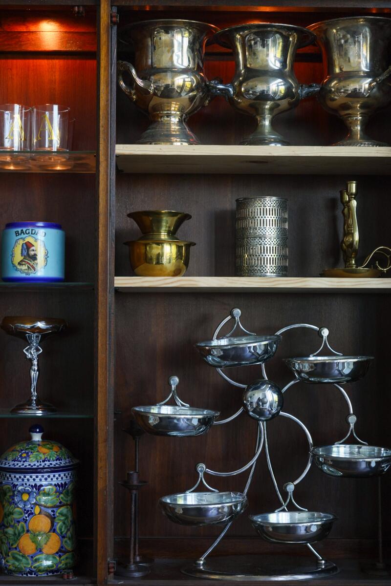 An assortment of vintage items sit on shelves in a china cabinet.