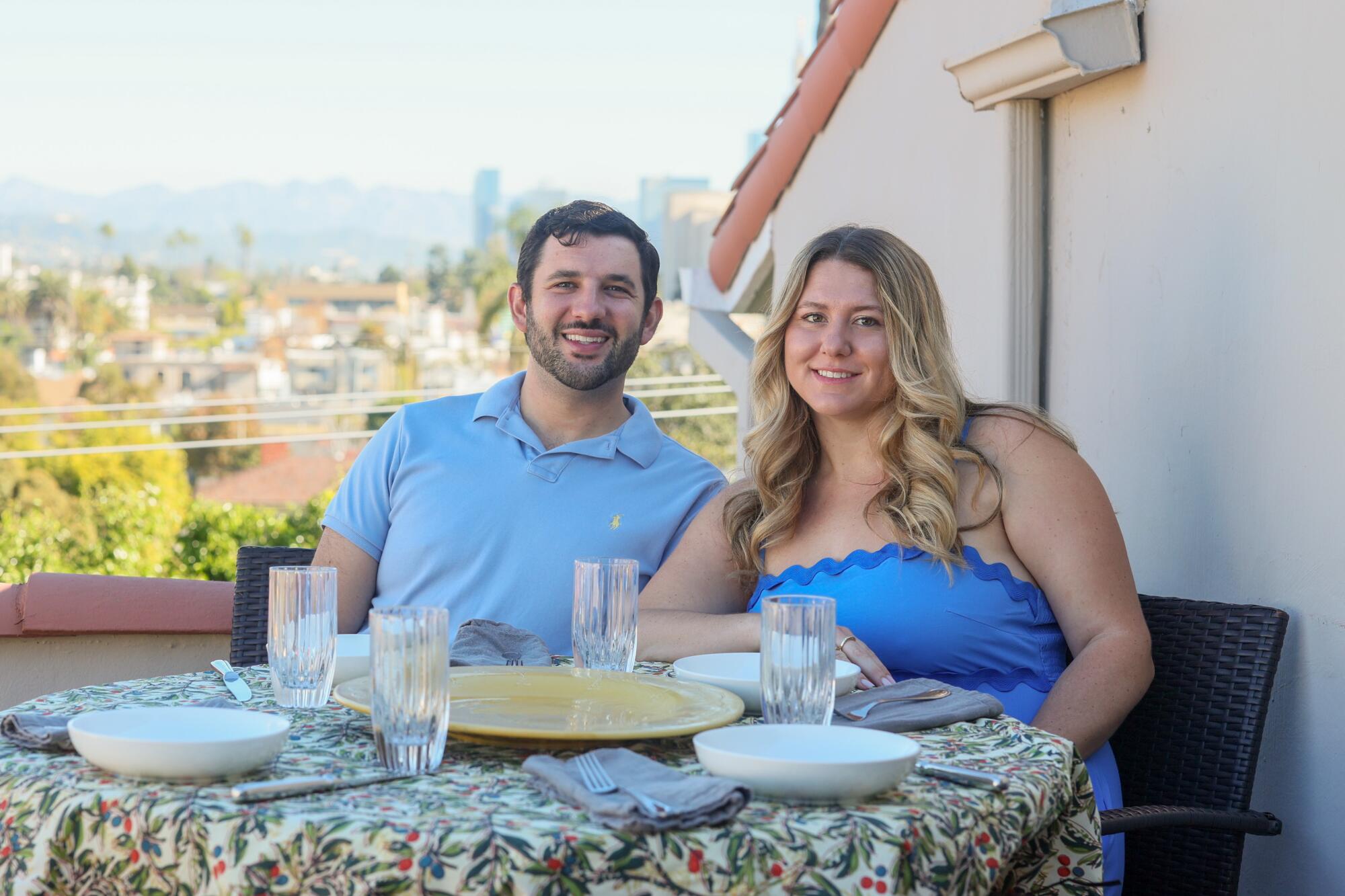 Two people sit at a table on the rooftop of their condo.