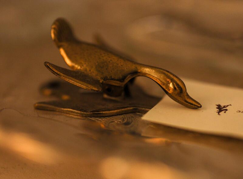 A bronze duck holds a business card.