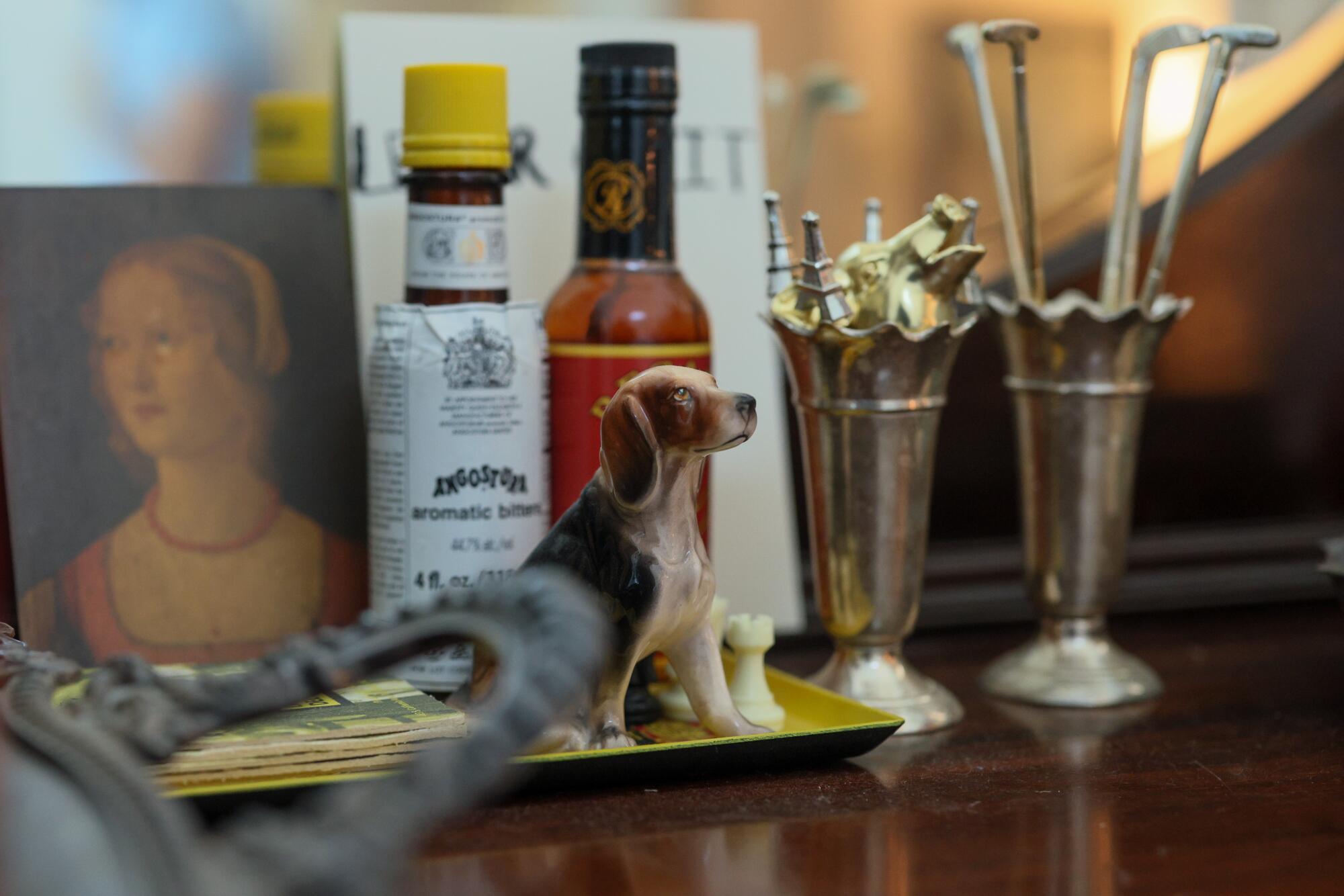 A small figure of a dog sits by other vintage cocktail items.