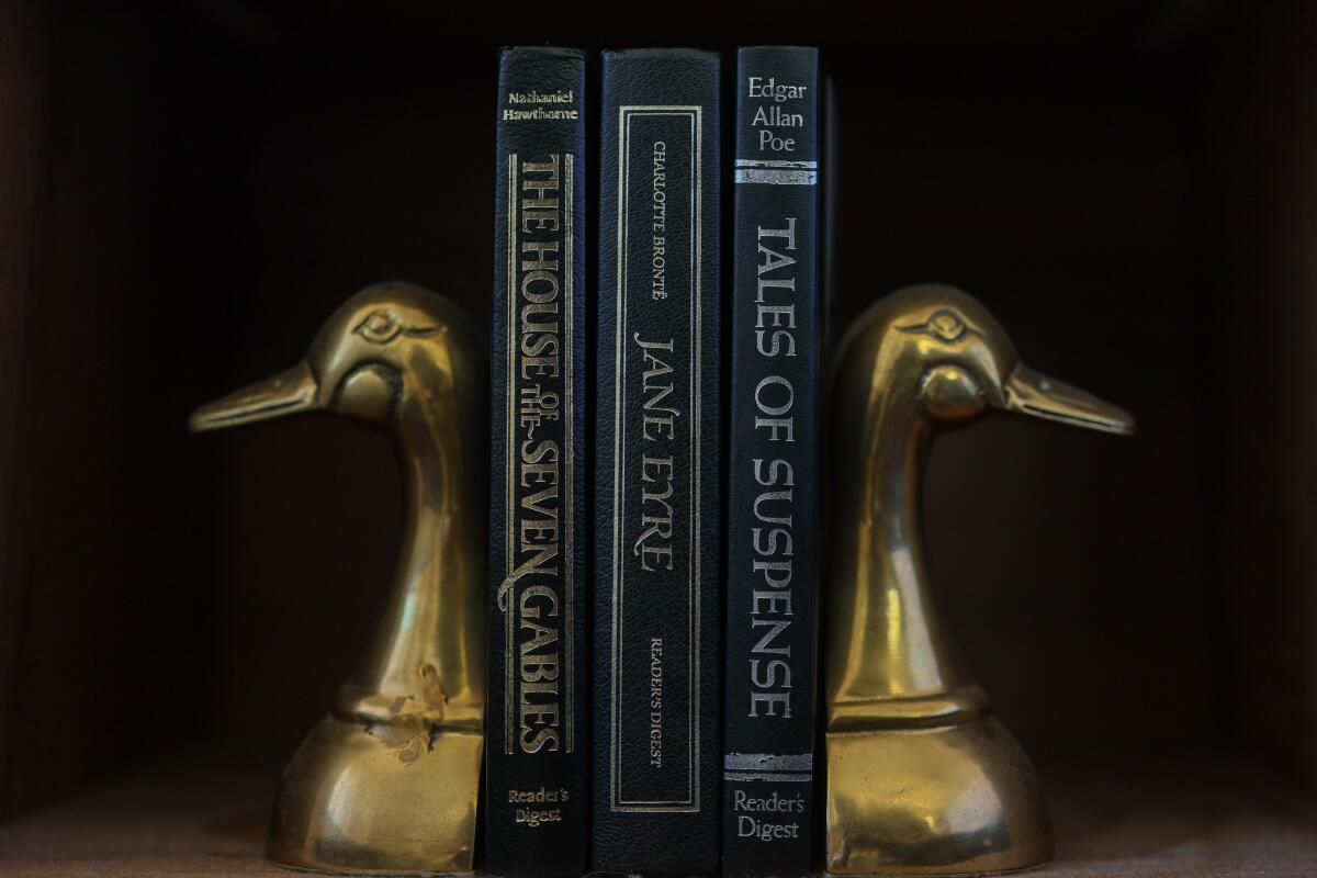 Leather-bound books are sandwiched in between brass duck bookends. 
