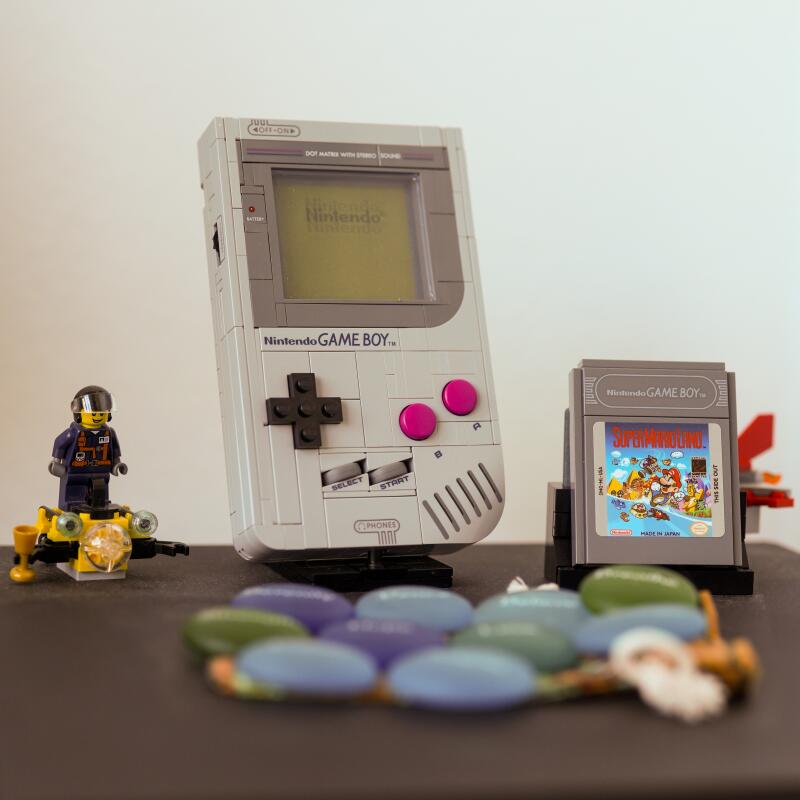 Legos, a Nintendo Game Boy and figuring sit on top of a Sony Playstation 4 console 