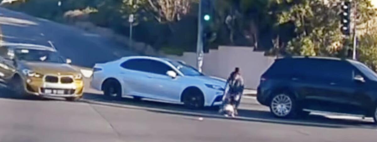 A screen shot from a video depicting a small child falling from the passenger side of a moving vehicle in Fullerton.