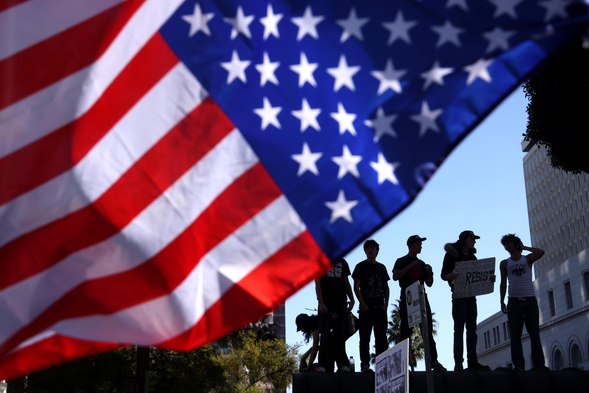 Protesters stand on top of a bus stop in downtown Los Angeles.