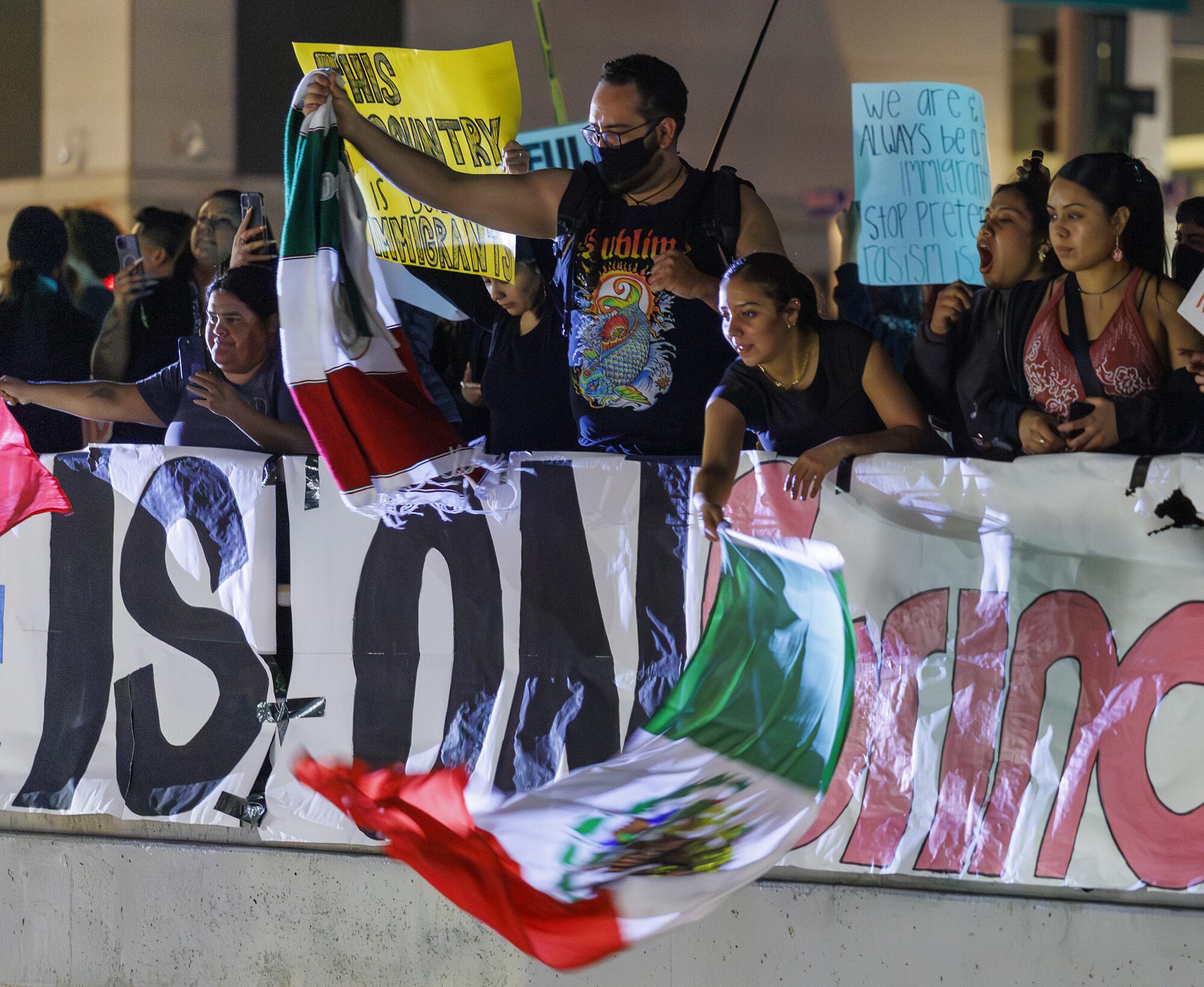 Protesters wave flags over the 101 freeway during a nationwide ICE Out protest.