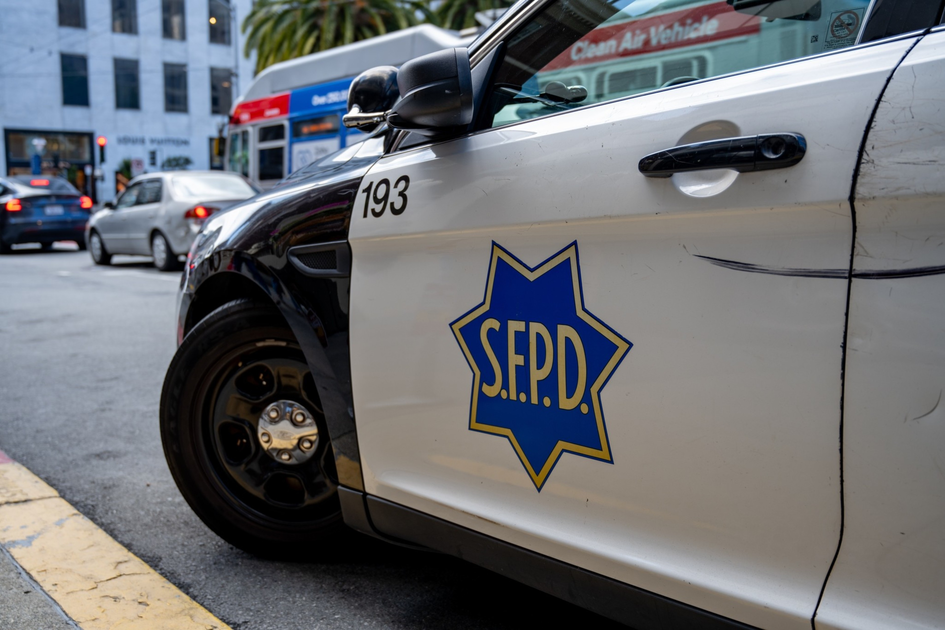 A train travels on an elevated track with a busy shipping port in the background. Shipping containers and cranes are visible under a cloudy sky.
