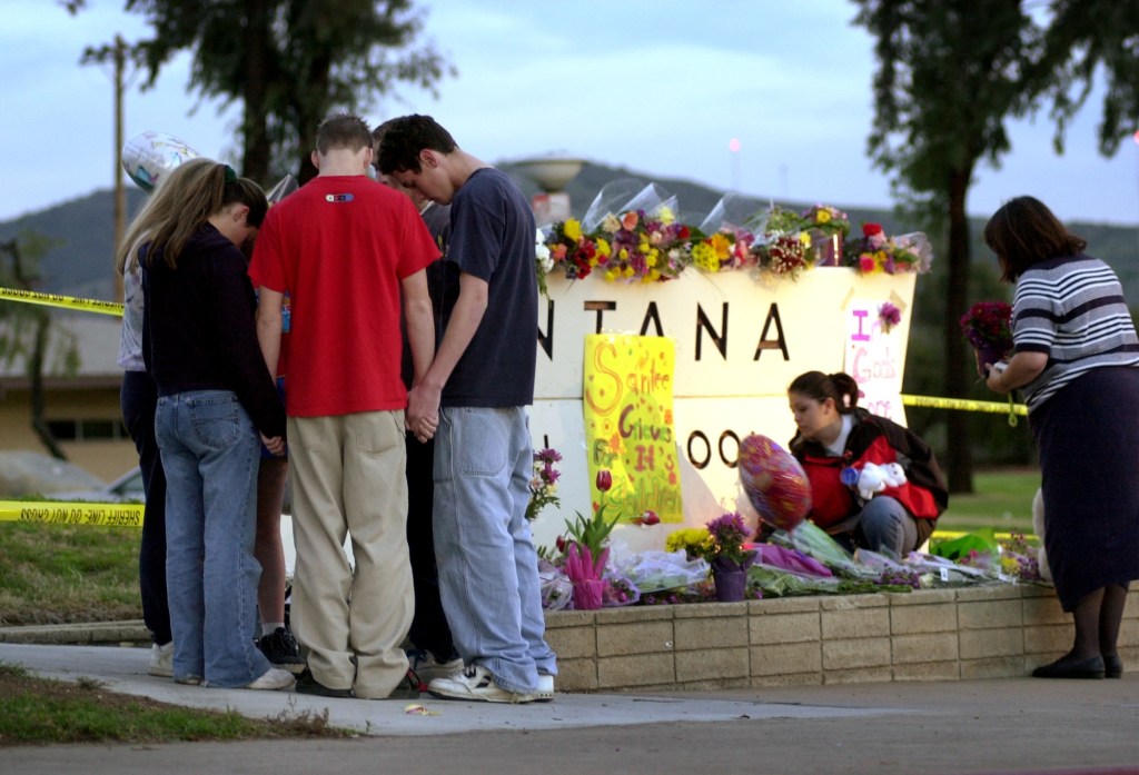 Students pray at a makeshift memorial for shooting victims at Santana High School.