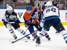 Edmonton Oilers forward Quinn Hutson battles with Winnipeg Jets defenceman Ville Heinola