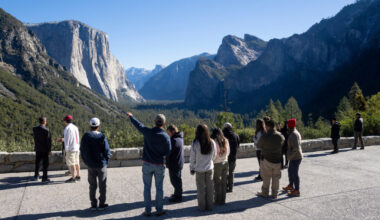 A teacher points towards Yosemite Valley in the distance as students look on