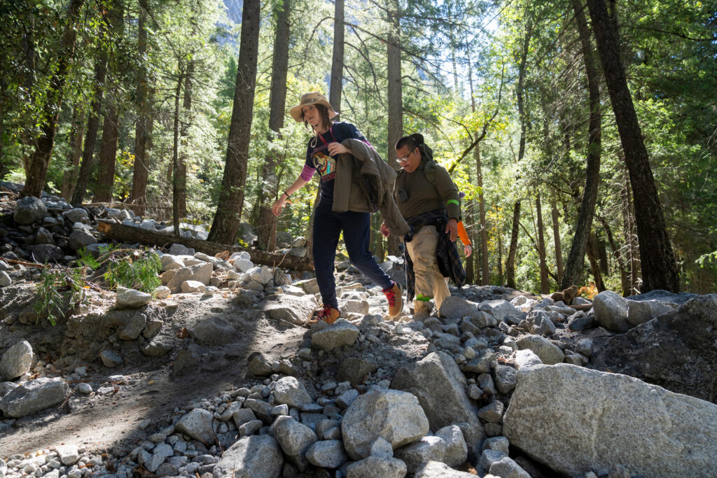 Two students walk through a rocky creek 