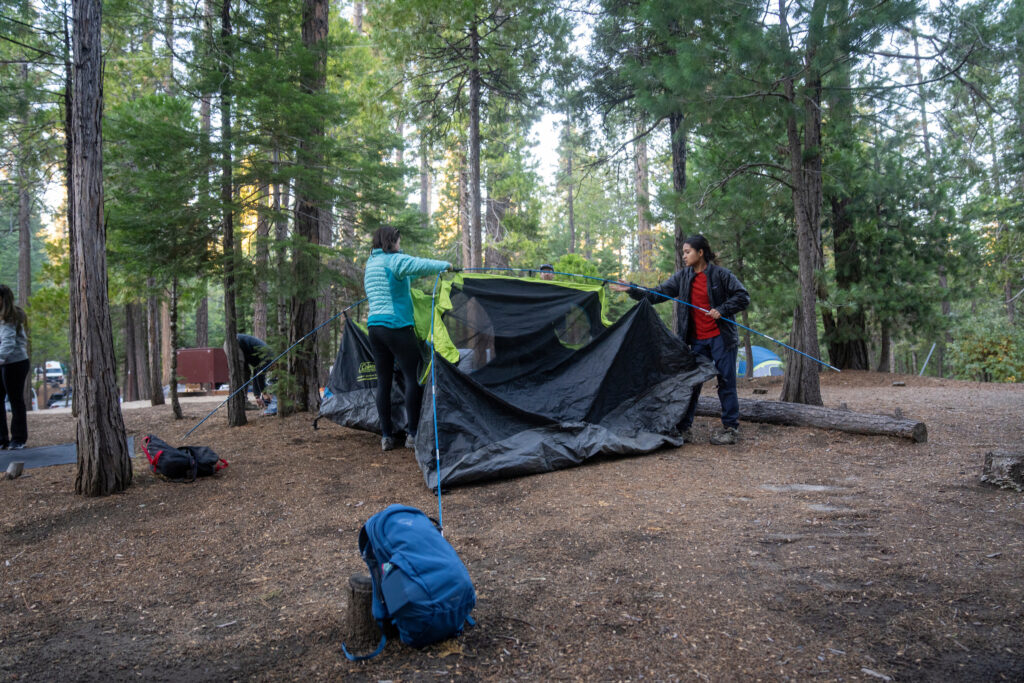 Two students setting up in a tent in the forest