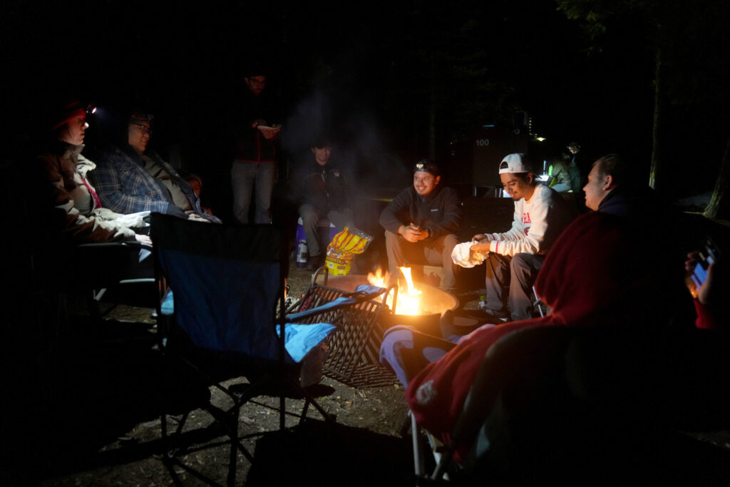 A group of students sitting around a campfire 