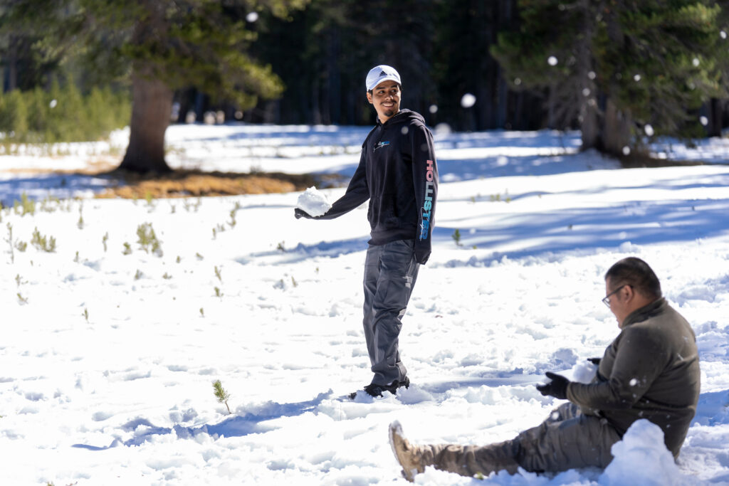 A student standing in a snowy field holding a snowball 