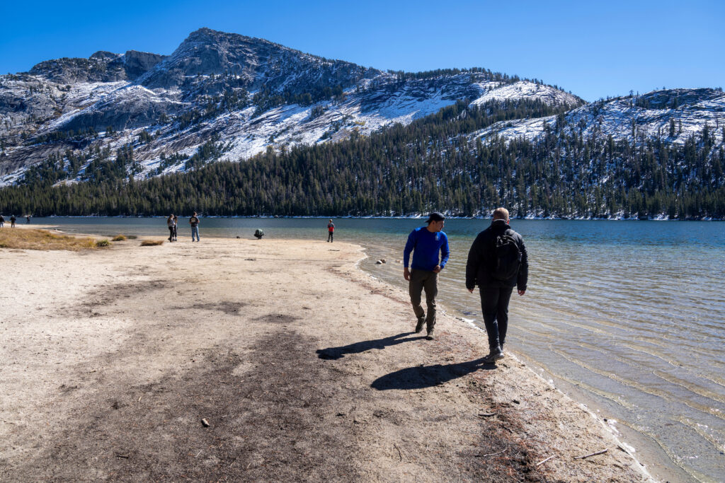 Group of students walking along a lake with a snowy mountain in the background 