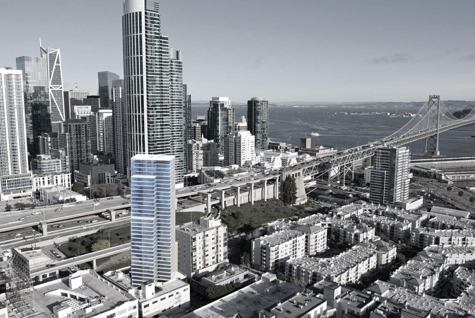 A tall modern building highlighted in blue stands among other skyscrapers near a bridge and waterfront in a cityscape.