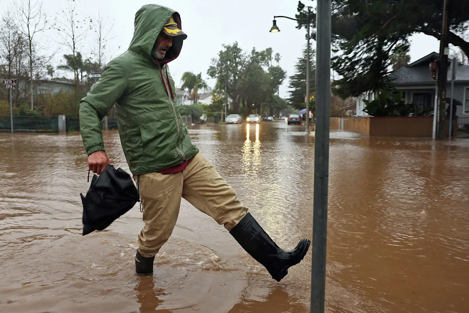 A person walks along a flooded street during a powerful long-duration atmospheric river storm on Feb. 4, 2024, in Santa Barbara, Calif. (Mario Tama/Getty Images)