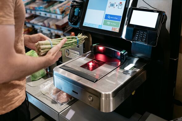 Close-up of unrecognizable man using self-checkout kiosk at grocery store