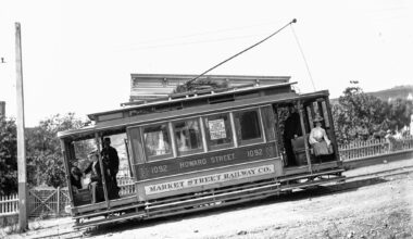 Historic streetcar labeled "Howard Street 1092" of the Market Street Railway Co. tilted on a dirt road with passengers and conductor visible.