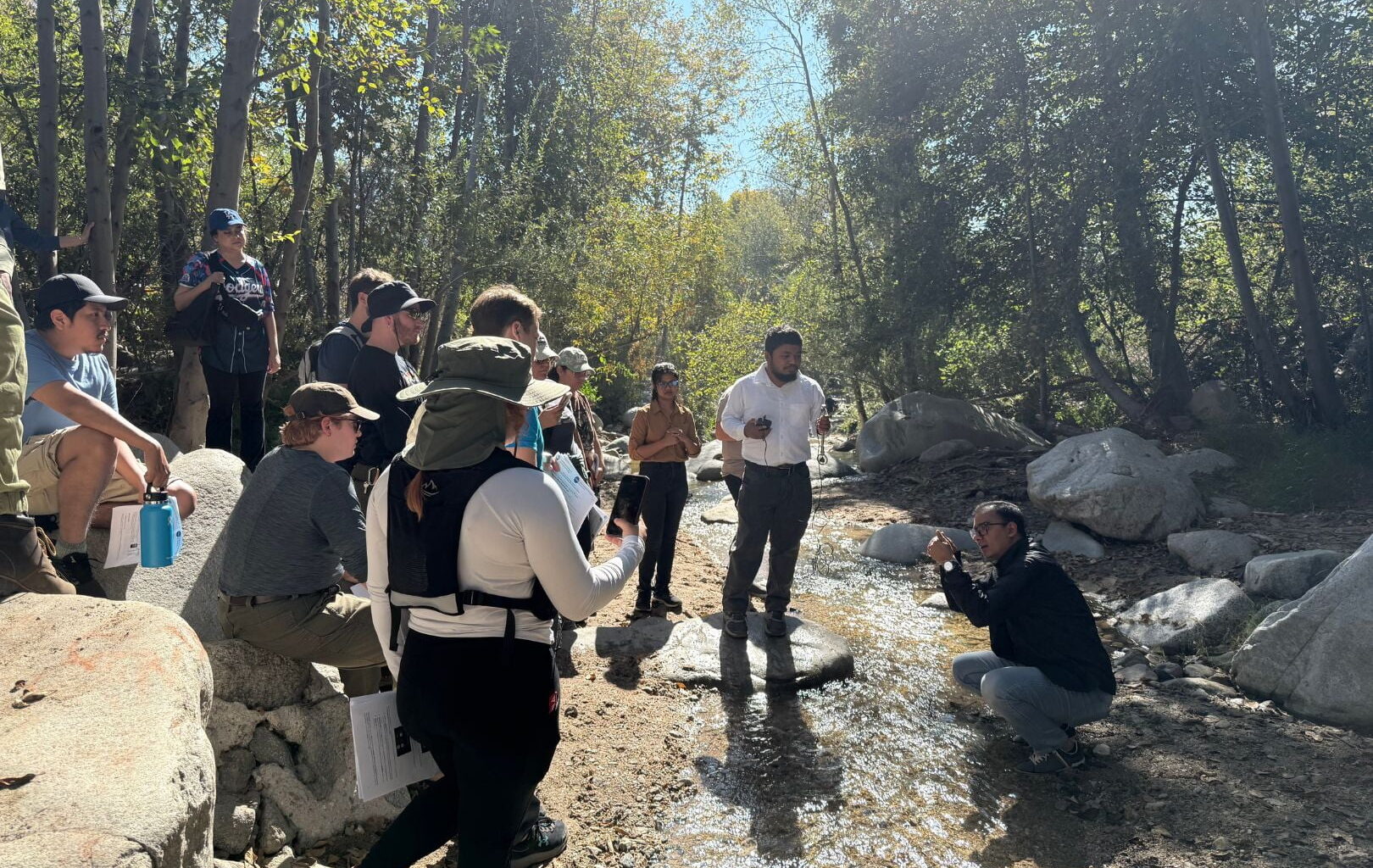 Image shows Dr. Adnan Rajib, lower right, in a creek  explaining water research to students " style=" height:1080px; width:1620px" _languageinserted="true" src="https://cdn.prod.web.uta.edu/-/media/80fcfbd2d29146ac87adc4601a95ba8f.jpg