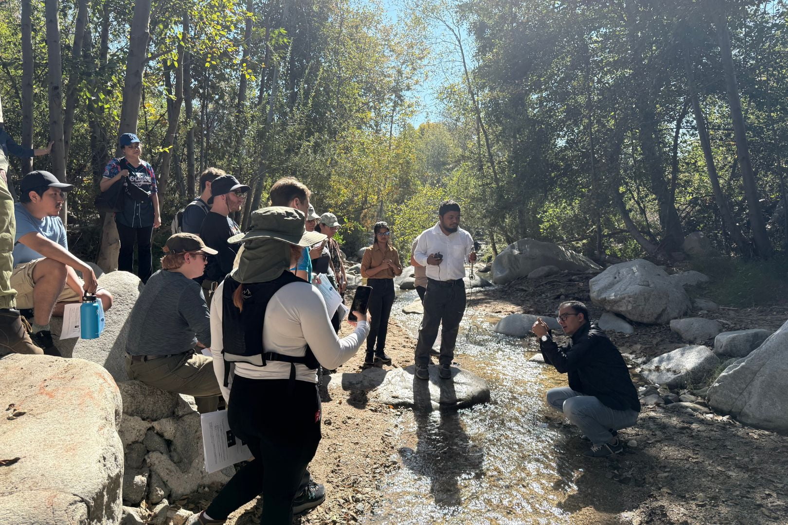 Image shows Dr. Adnan Rajib, lower right, in a creek  explaining water research to students " style=" height:1080px; width:1620px" _languageinserted="true" src="https://cdn.prod.web.uta.edu/-/media/80fcfbd2d29146ac87adc4601a95ba8f.jpg