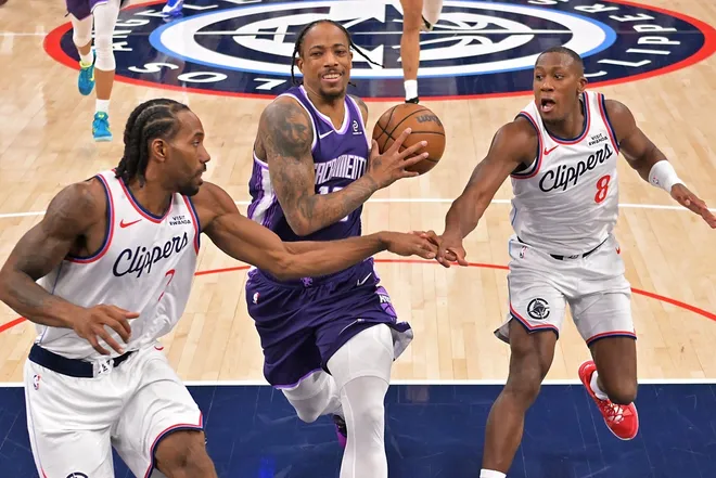 Dec 30, 2025; Inglewood, California, USA; Los Angeles Clippers forward Kawhi Leonard (2) and guard Kris Dunn (8) defend Sacramento Kings guard Demar Derozan (10) as he drives to the basket in the second half at Intuit Dome.