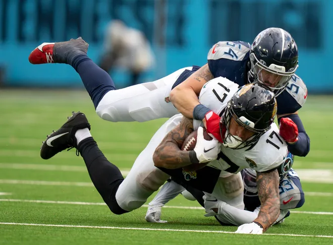 Jacksonville Jaguars tight end Evan Engram (17) is brought down after a catch by Garret Wallow (54) and Tennessee Titans cornerback Eric Garror (33) during their game at Nissan Stadium in Nashville, Tenn., Sunday, Jan. 7, 2024.