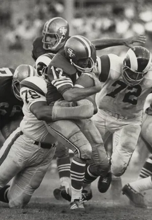 San Francisco 49ers quarterback John Brodie is brought down during a preseason game by Los Angeles Rams defensive tackle Roger Brown (78) and Diron Talbert (72).