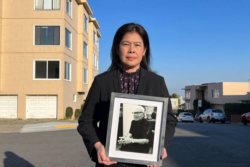 Monthanus Ratanapakdee holds a photo of her father, Vicha Ratanapakdee, in January 2022, in front of the San Francisco apartment building where he was attacked a year earlier. Photo: AP