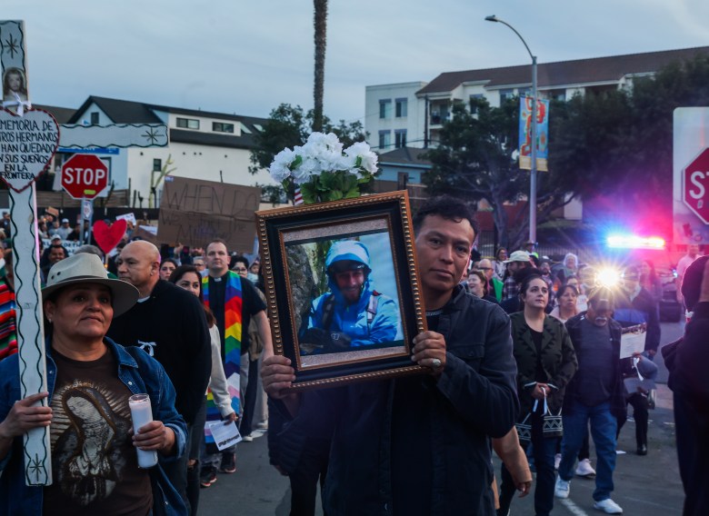A man holds a photo of Alex Pretti, who was shot and killed by a border agent in Minneapolis over the weekend, during a Barrio Logan march for victims of ICE violence in Minneapolis and beyond. (Photo by Adrian Childress/Times of San Diego)