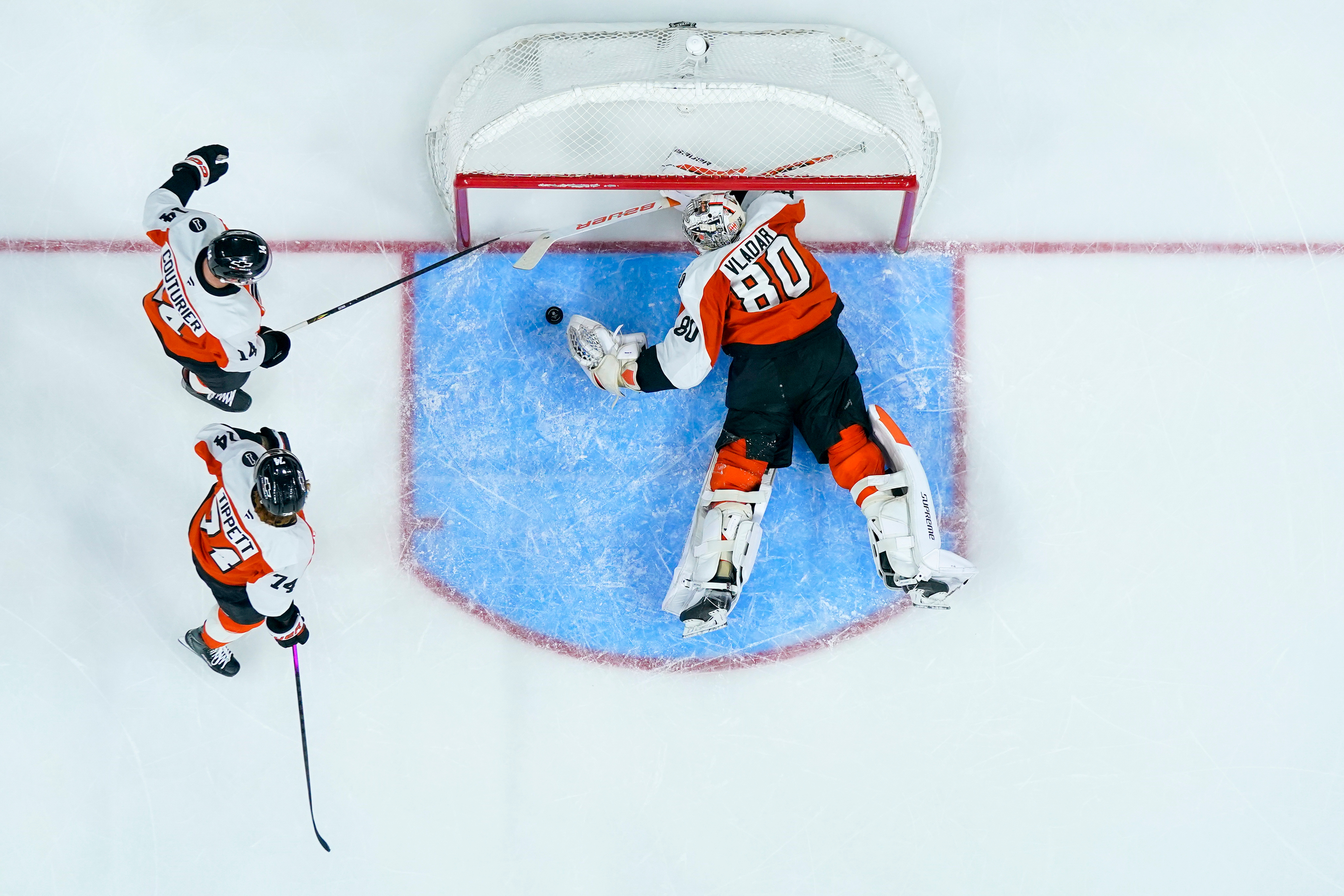 Philadelphia Flyers goaltender Dan Vladar, right, covers up the puck...