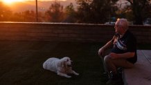 Ted Koerner, whose home was reduced to ash in the 2025 wildfires, sits on the porch of his newly rebuilt home, alongside his dog Daisy Mae, in Altadena, Calif., Dec. 11, 2025.