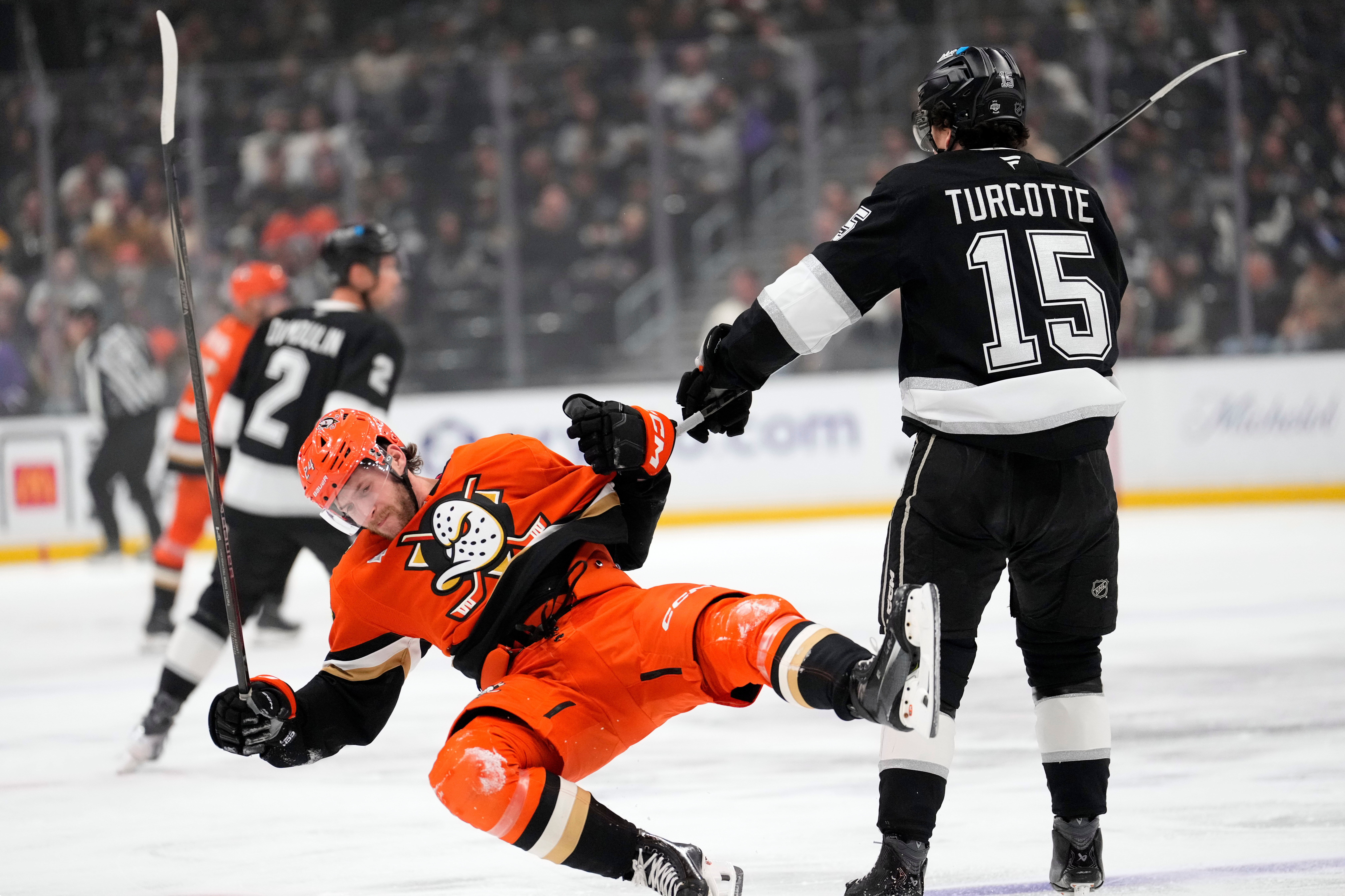 Ducks center Jansen Harkins, left, is shoved to the ice...