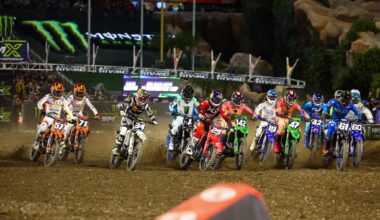 A row of dirt bikes speeds off the start grid of a supercross race.