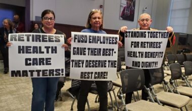 Attendees at Wednesday, Jan. 14, 2026, night’s Fresno Unified board meeting brought signs addressing concerns over retiree health insurance. (GV Wire/Jahziel Tello)
