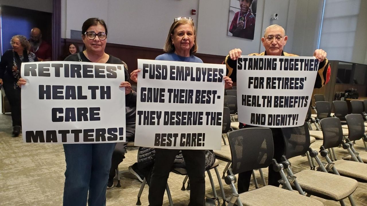 Attendees at Wednesday, Jan. 14, 2026, night’s Fresno Unified board meeting brought signs addressing concerns over retiree health insurance. (GV Wire/Jahziel Tello)