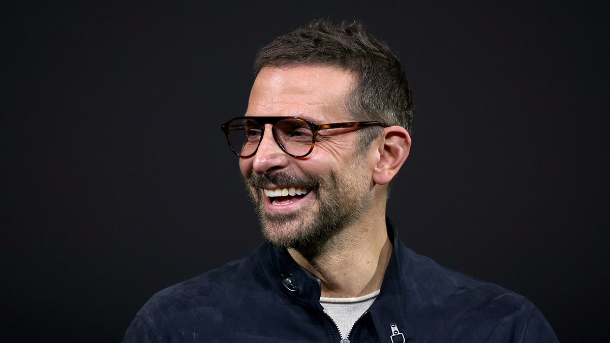 Bradley Cooper smiles while wearing glasses