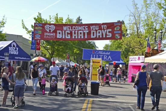 Welcome sign hangs over street as people check out different vendor booths