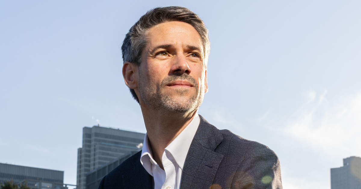 A white dome-shaped government building with columns stands before a blue semicircle, framed by a red border on the left and top sides.