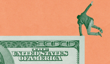 A modern two-story house with large windows, wood paneling, and a paved driveway, surrounded by lush green trees and manicured garden beds.