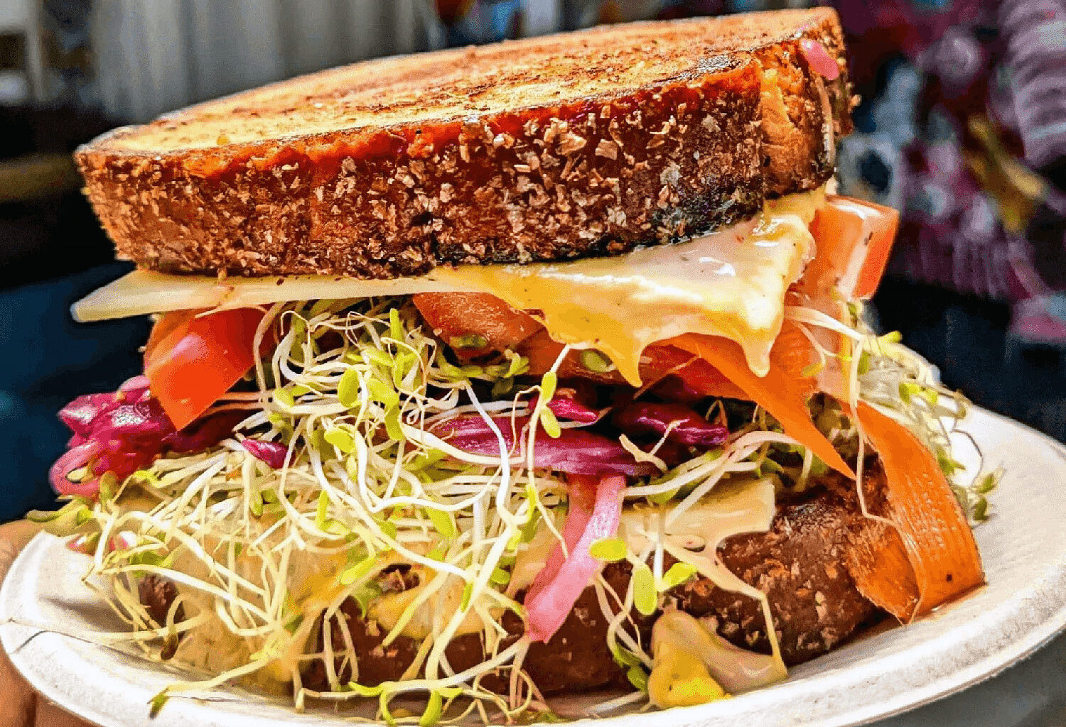 Sandwich with sprouts, onions, carrots and other veggies on seeded bread.