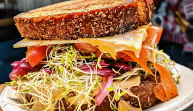 Sandwich with sprouts, onions, carrots and other veggies on seeded bread.