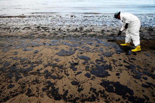 FILE - A worker removes oil from sand at Refugio State Beach, north of Goleta, Calif., May 21, 2015. (AP Photo/Jae C. Hong, File)
