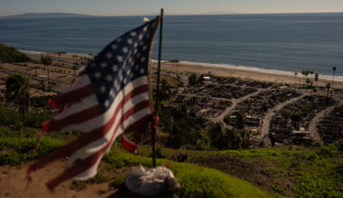 A tattered U.S. flag flaps in the wind over the remains of a mobile home park that was destroyed in...