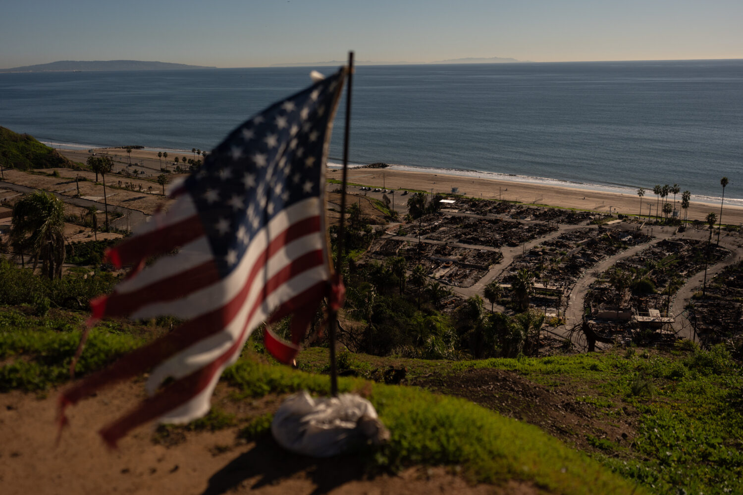 A tattered U.S. flag flaps in the wind over the remains of a mobile home park that was destroyed in...