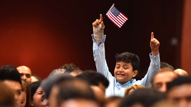 A young relative of a new citizen cheers from the crowd of immigrants.