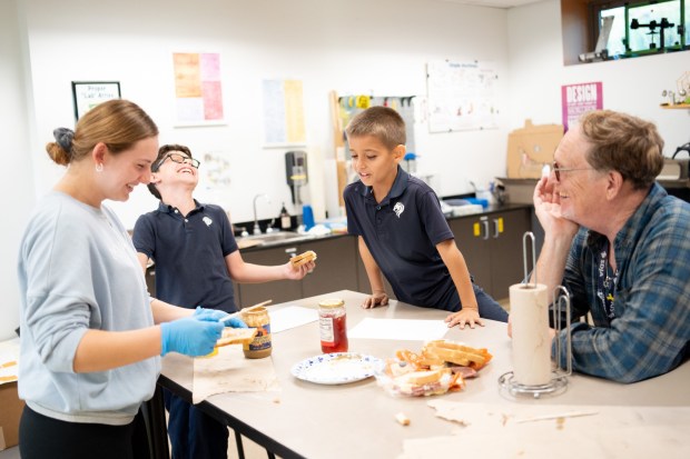The MUS Lions robotics team created an outreach arm called Running Start Robotics. One standout lesson taught younger students to think like engineers by writing clear, detailed instructions for making a peanut butter and jelly sandwich. Here, 11th grader Sophia Monsowitz, the main force behind it, is trying to make a sunbutter jelly sandwich based on the instructions the Kayafet students gave her. (Courtesy of SDJA)