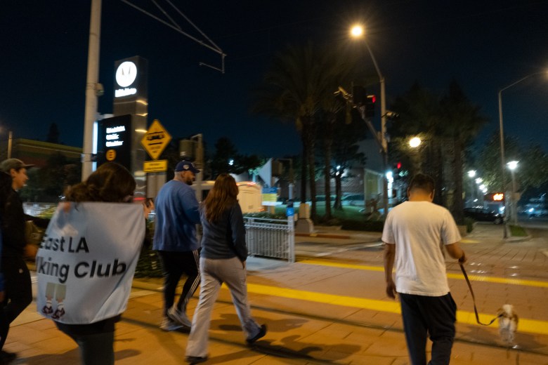 Members of the East LA Walking Club cross 3rd Street with a dog on a leash