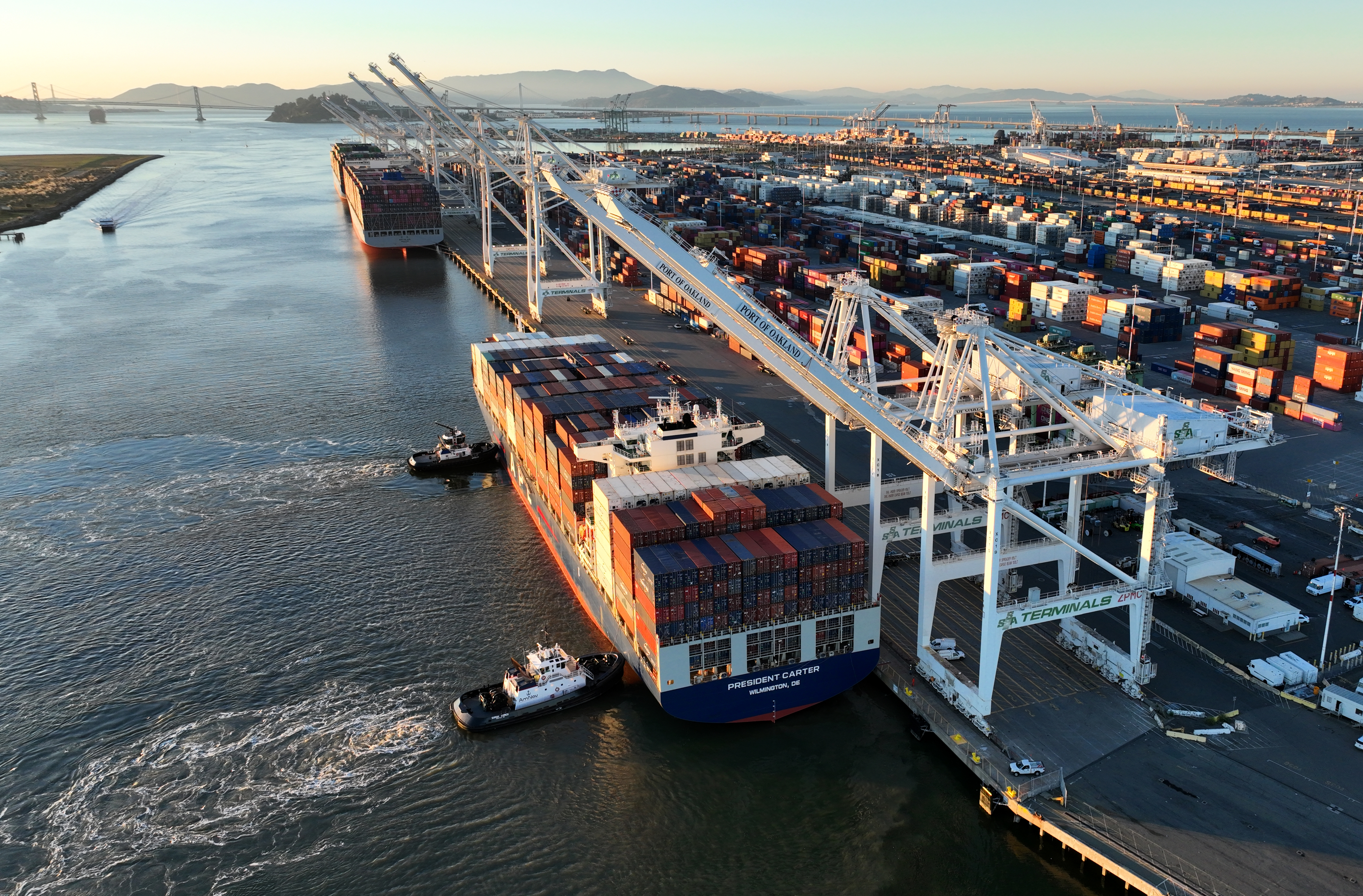 Tugboats help a container ship dock in an aerial view...
